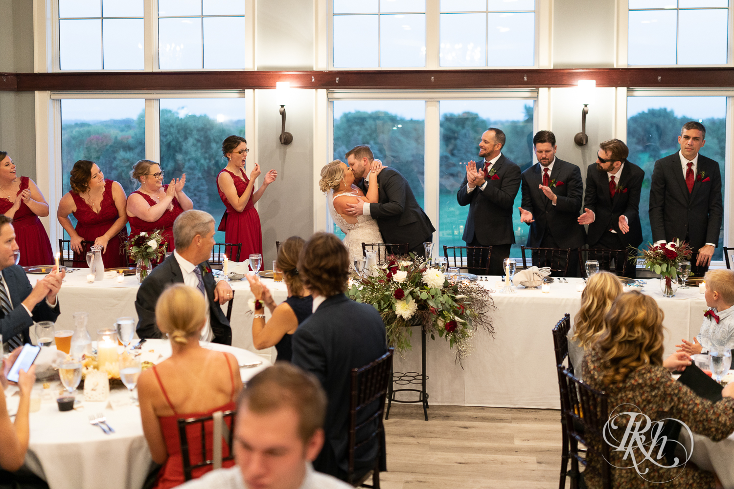 Bride and groom kiss at head table during reception at Hastings Golf Club in Hastings, Minnesota.