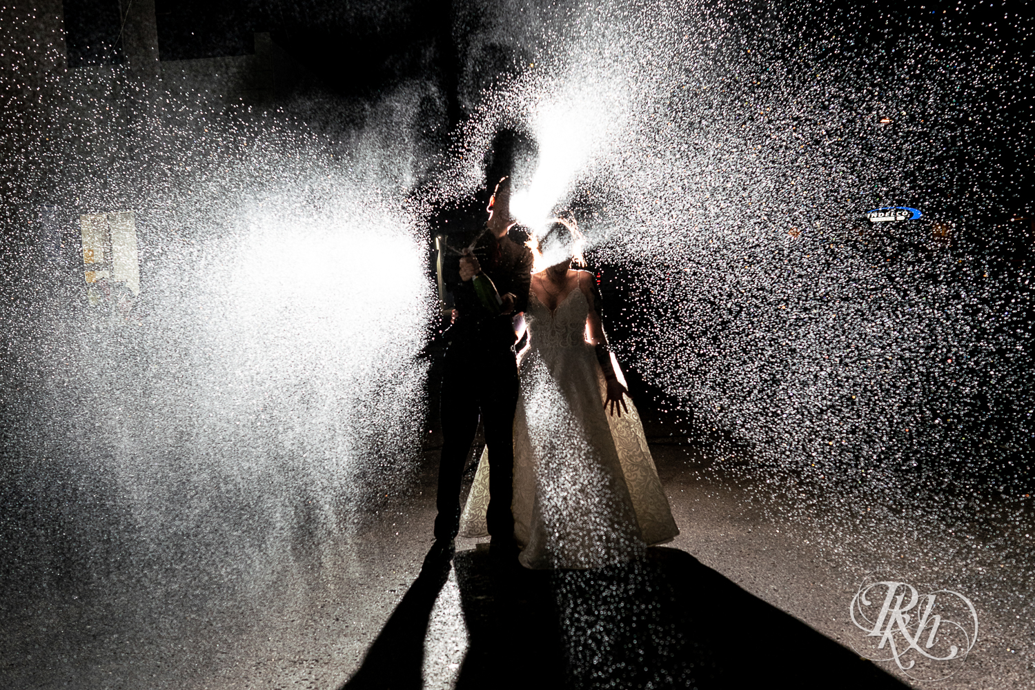 Tattooed bride and groom spray champagne at night at Warehouse Winery in Saint Louis Park, Minnesota.