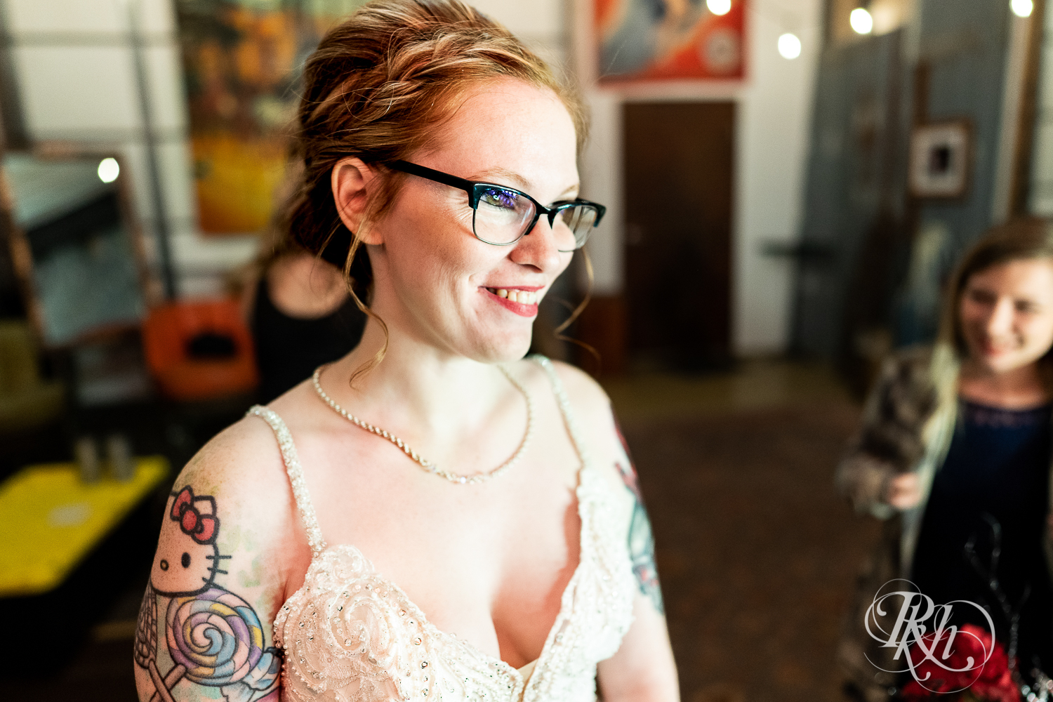 Tattooed bride with glasses smiling at Warehouse Winery in Saint Louis Park, Minnesota.