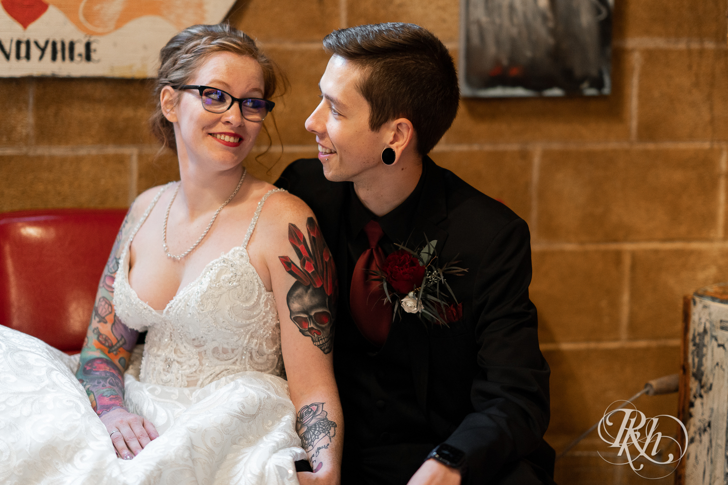 Tattooed bride and groom sitting and smiling at Warehouse Winery in Saint Louis Park, Minnesota.