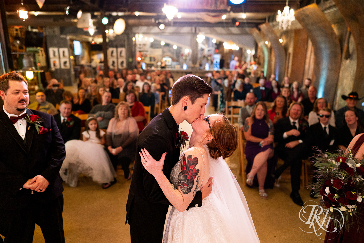 Bride and groom kissing at alter with guests in the background at Warehouse Winery in Saint Louis Park, Minnesota.
