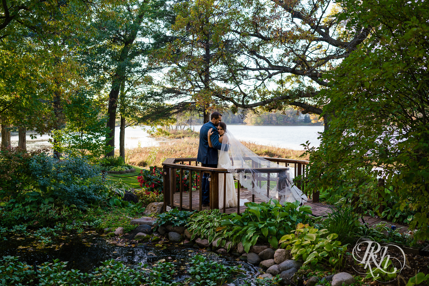 Bride and groom hugging on the bridge at The Chart House in Lakeville, Minnesota.