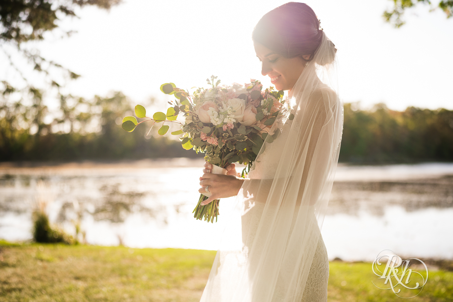 Bride holds flowers in the sunset at The Chart House in Lakeville, Minnesota.