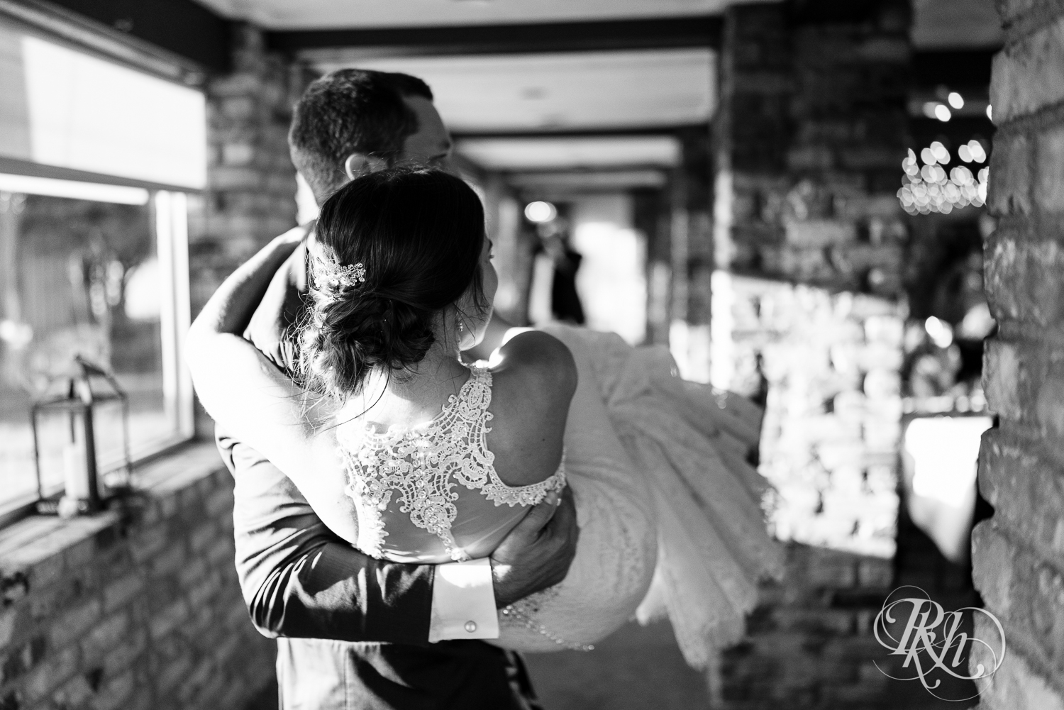 Groom carries bride into the reception at The Chart House in Lakeville, Minnesota.