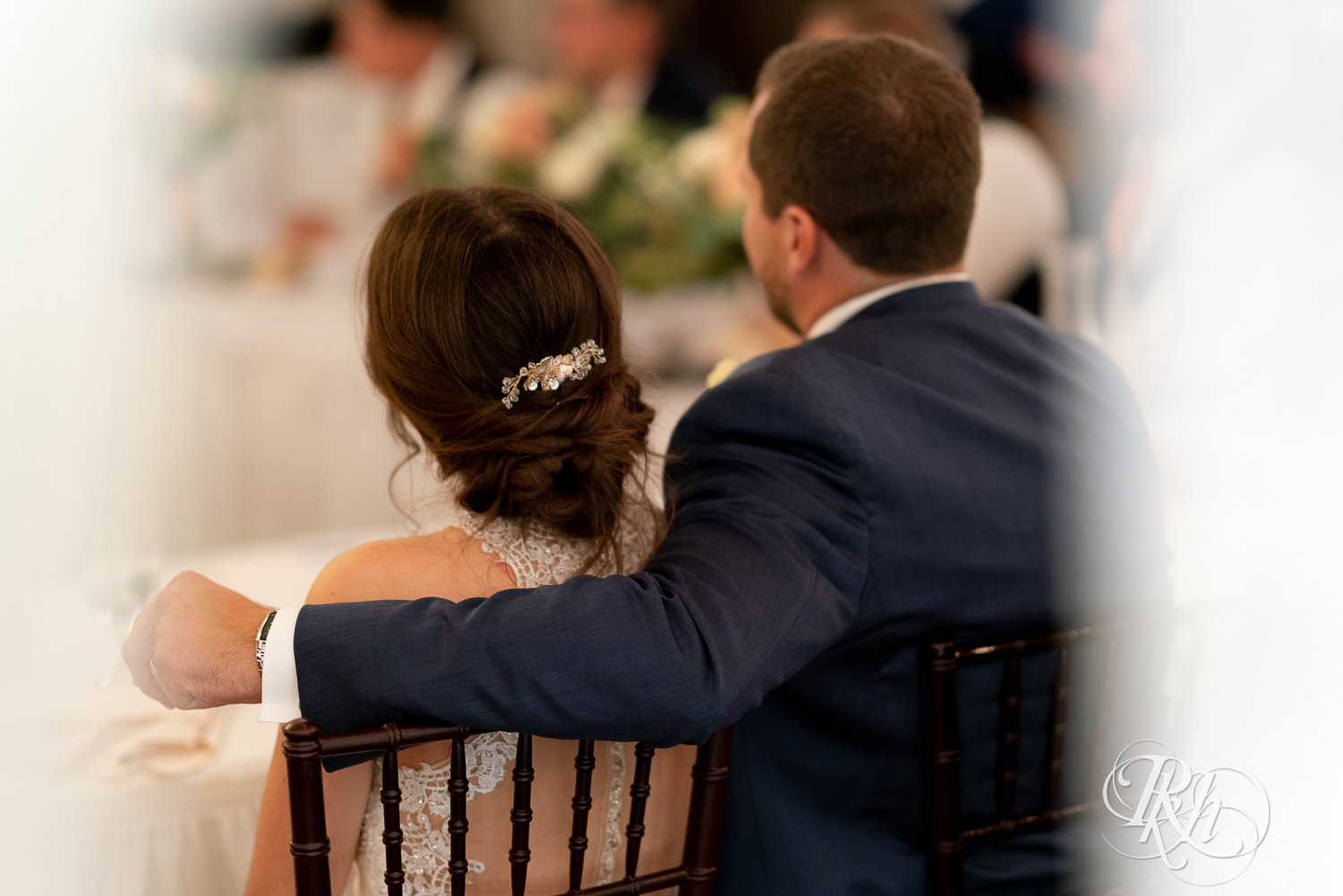 Groom wraps arm around bride during reception at The Chart House in Lakeville, Minnesota.