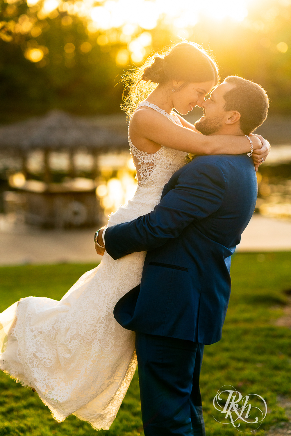 Groom lifts bride during sunset at The Chart House in Lakeville, Minnesota.