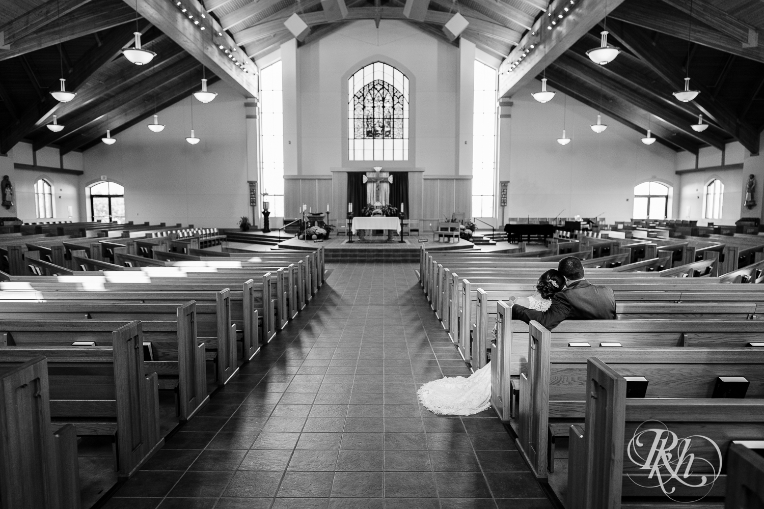 Bride and groom sitting in pews at Saint Joseph Catholic Church in Rosemount, Minnesota.