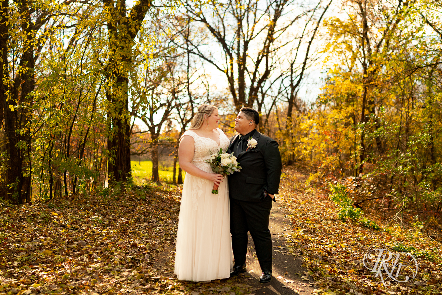 Lesbian brides smile in fall leaves at the Eagan Community Center in Eagan, Minnesota.