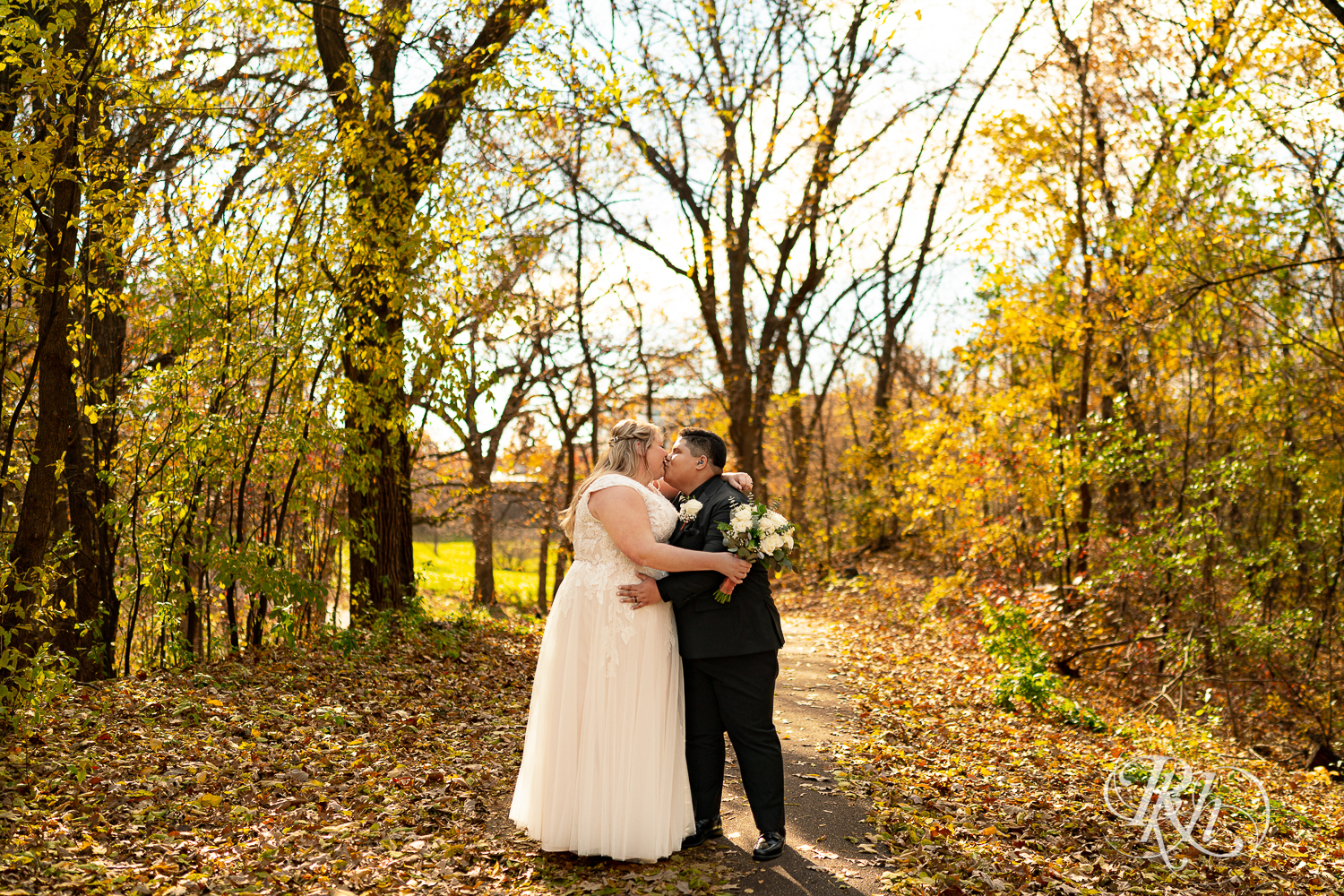 Lesbian brides kiss in fall leaves at the Eagan Community Center in Eagan, Minnesota.