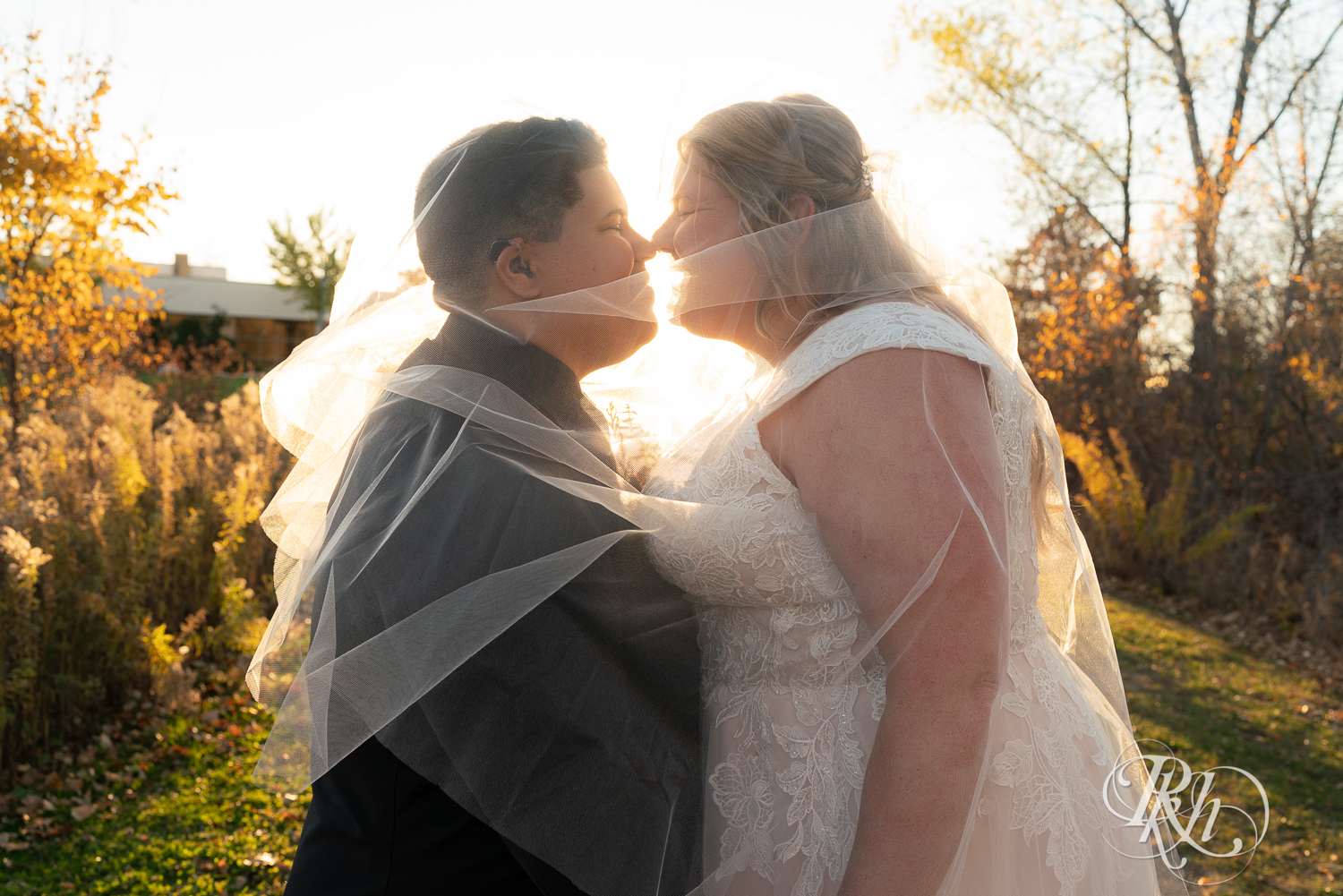 Lesbian brides under veil at sunset at Eagan Community Center in Eagan, Minnesota.