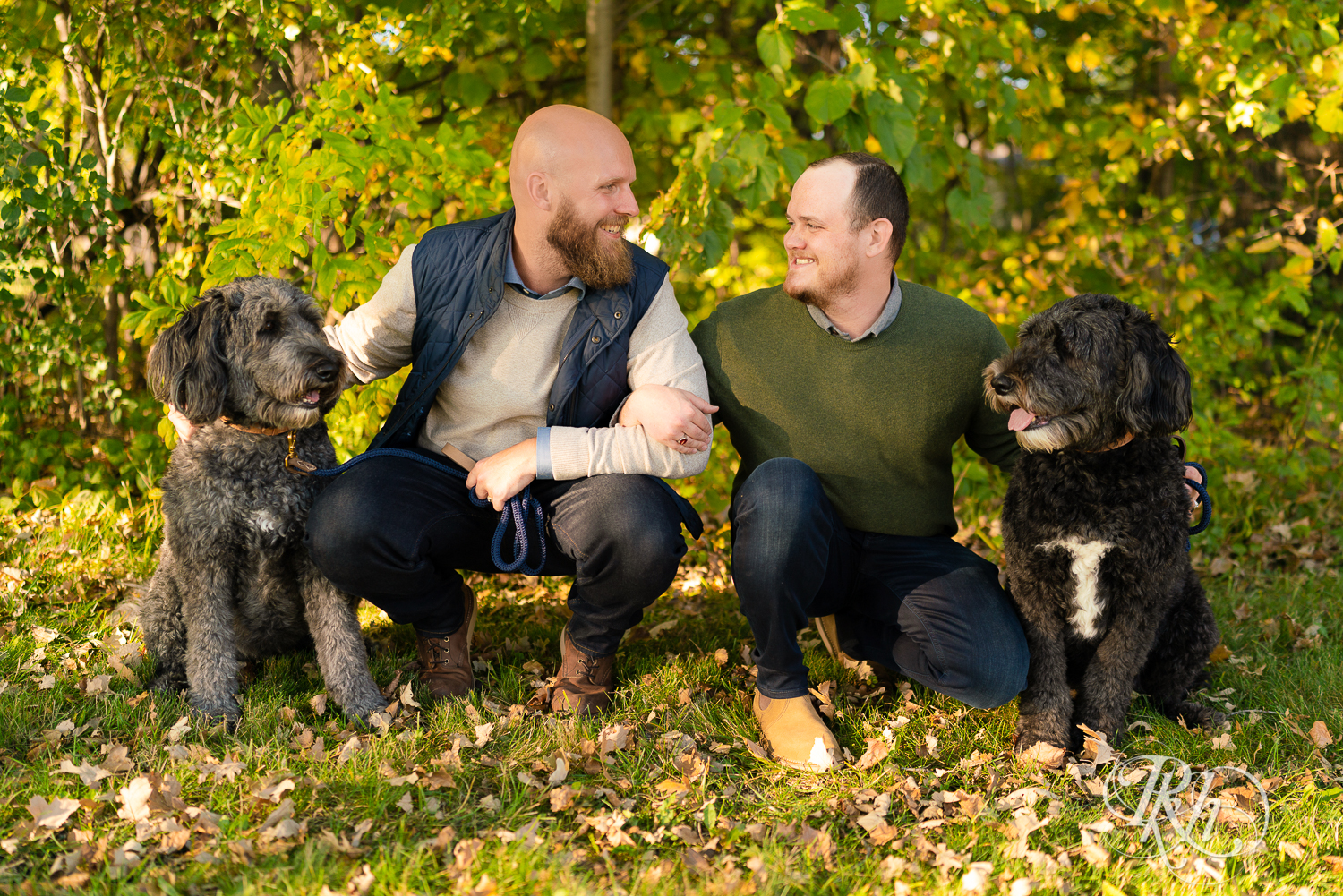Two gay men laughing and smiling with their Poodles.