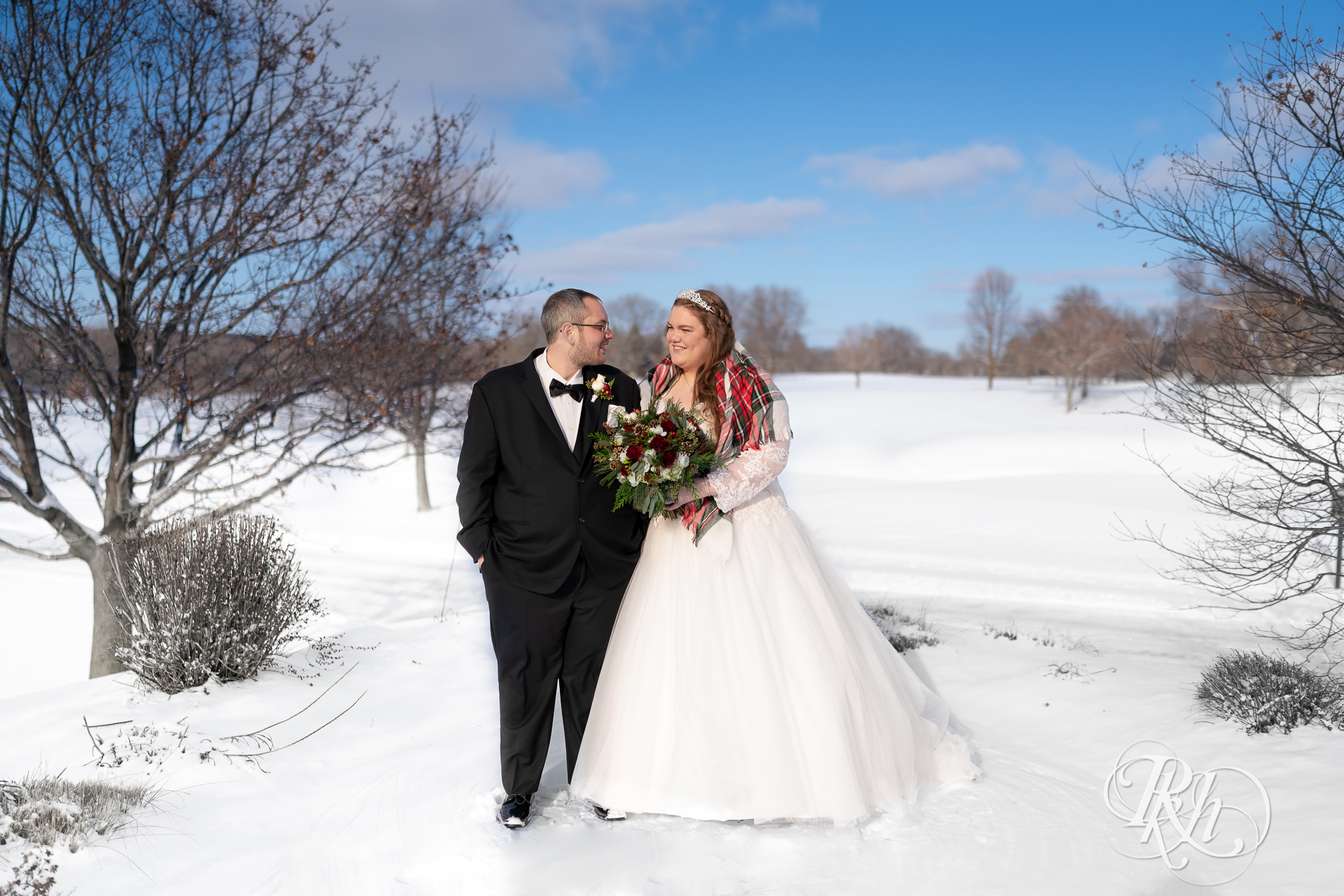 Bride and groom smiling in the snow at Christmas wedding at Oak Glen Golf Course in Stillwater, Minnesota.