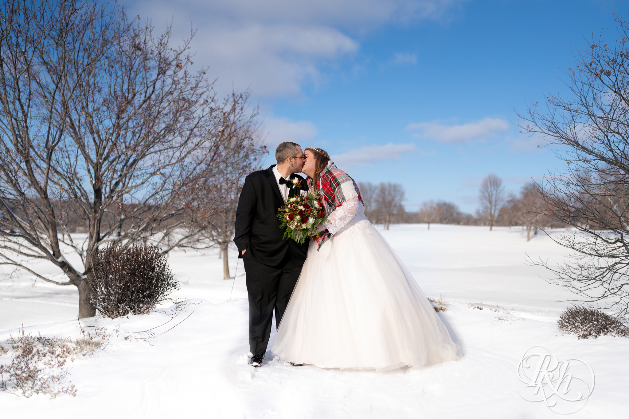 Bride and groom kissing in the snow at Christmas wedding at Oak Glen Golf Course in Stillwater, Minnesota.