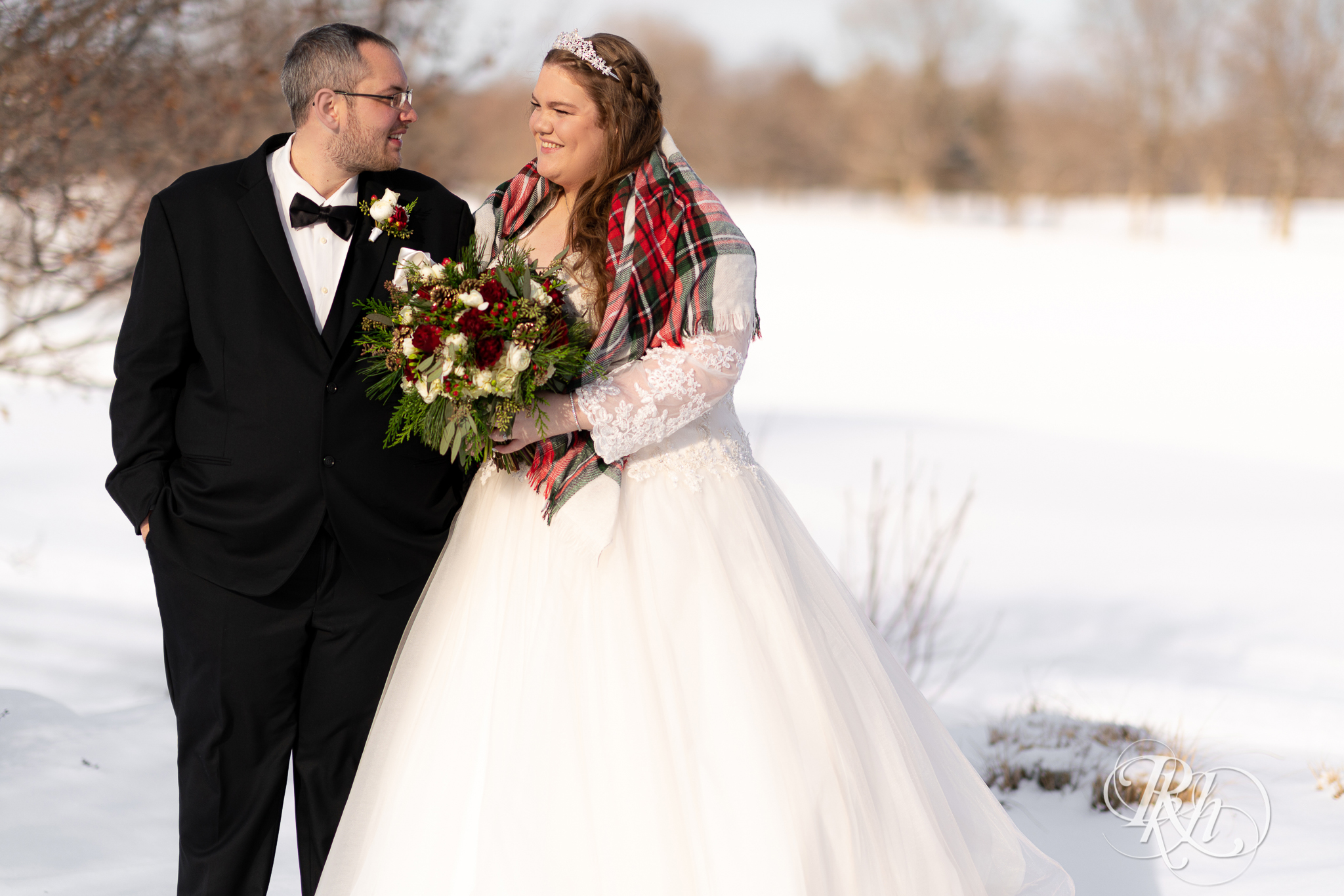 Bride and groom smiling in the snow at Christmas wedding at Oak Glen Golf Course in Stillwater, Minnesota.