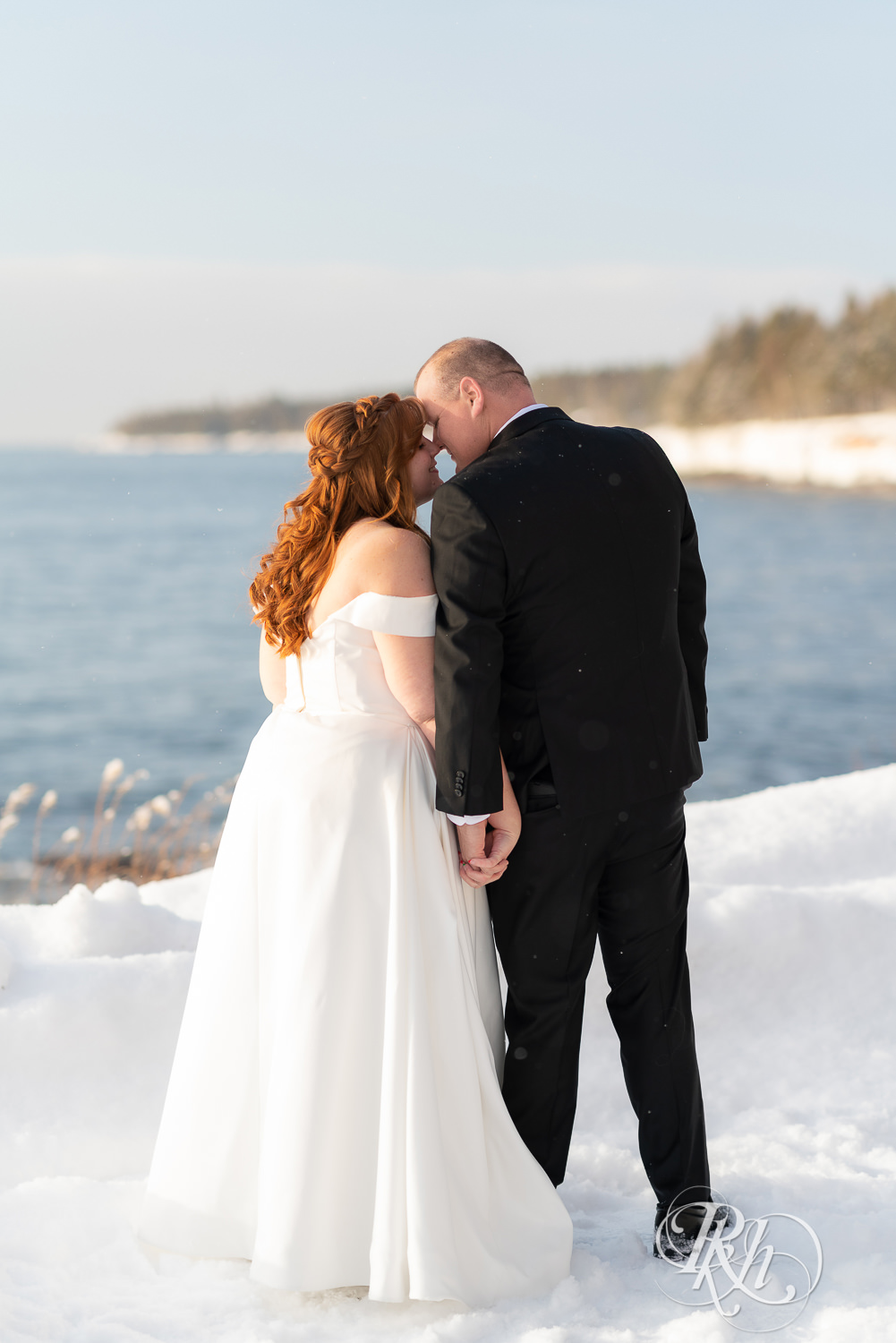 Bride and groom kissing in the snow in front of Lake Superior at Grand Superior Lodge in Two Harbors, Minnesota.