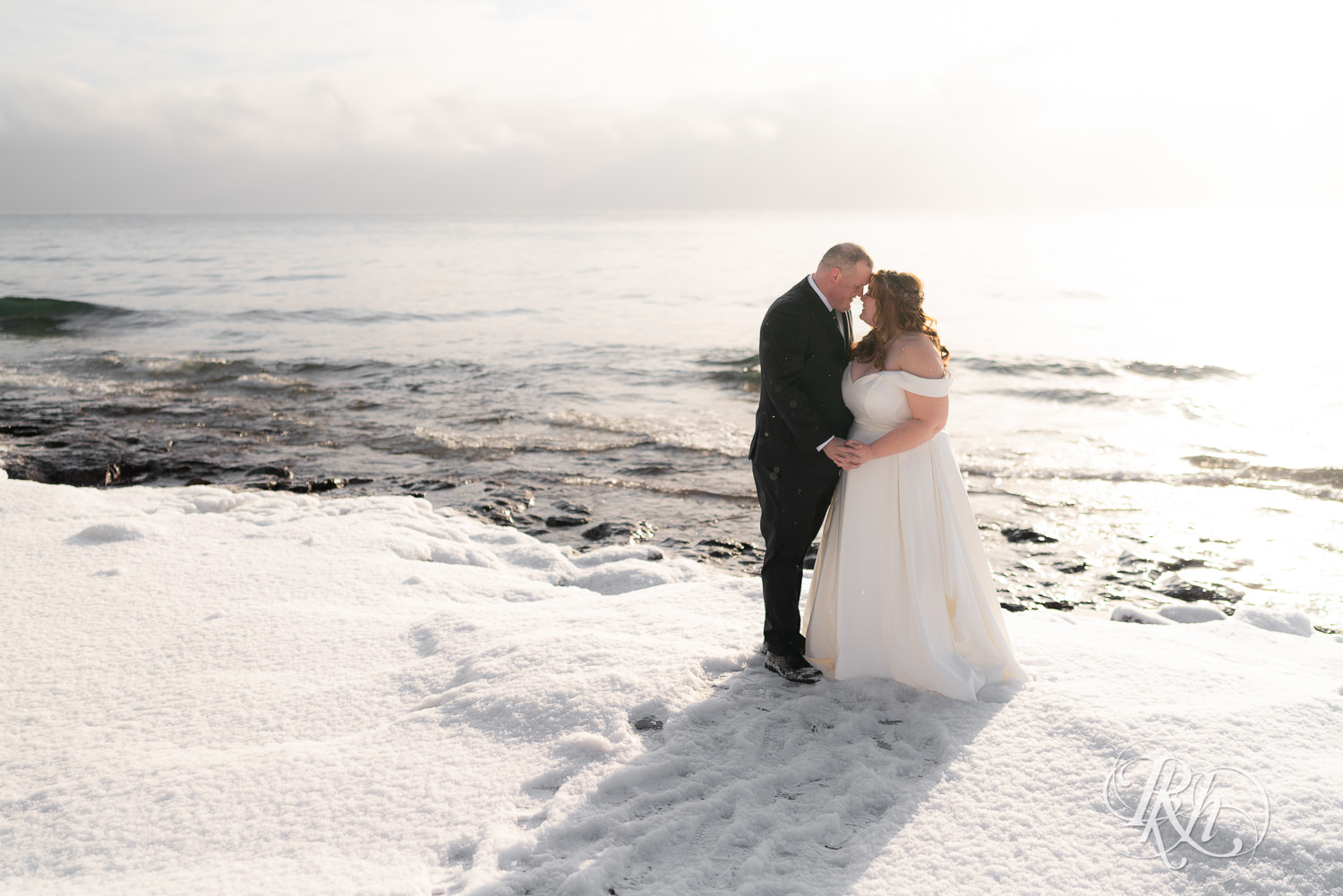 Bride and groom kissing in the snow in front of Lake Superior at Grand Superior Lodge in Two Harbors, Minnesota.