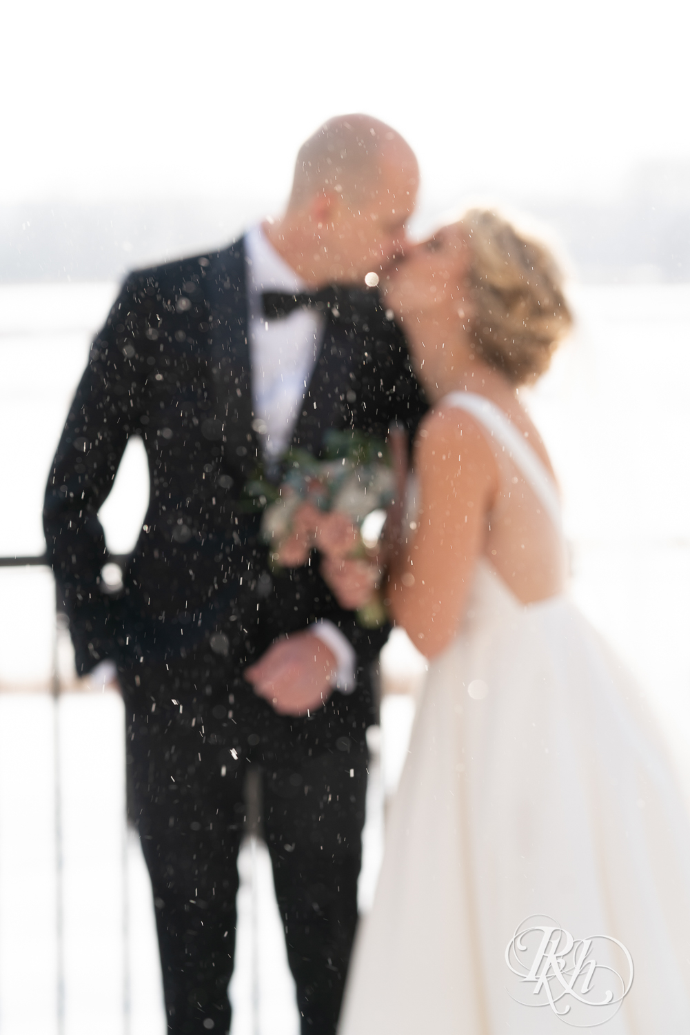 Bride and groom kissing in falling snow at Braemar Golf Course in Edina, Minnesota.
