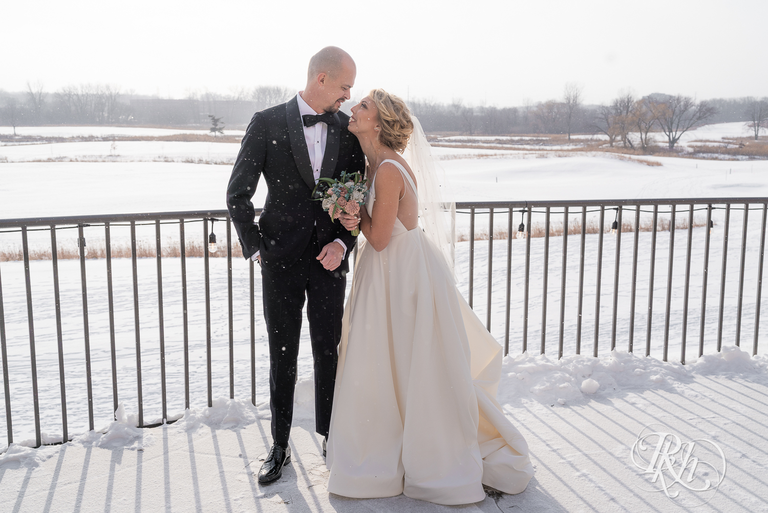 Bride and groom smiling in falling snow at Braemar Golf Course in Edina, Minnesota.