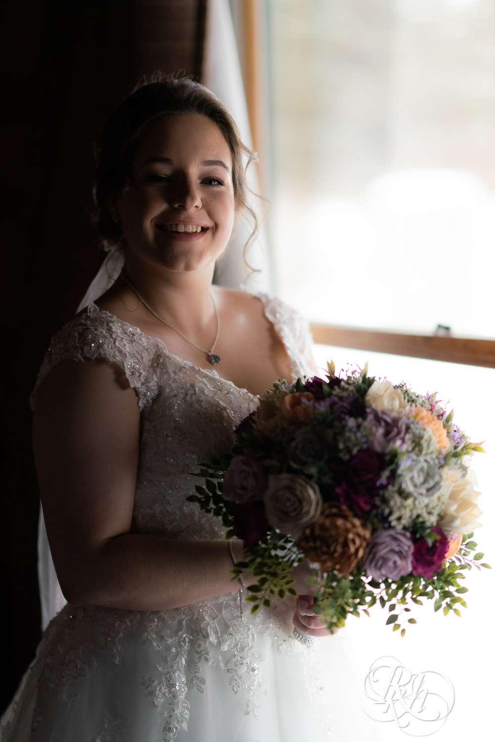Bride smiling and holding flowers at Glenhaven Events in Farmington, Minnesota.