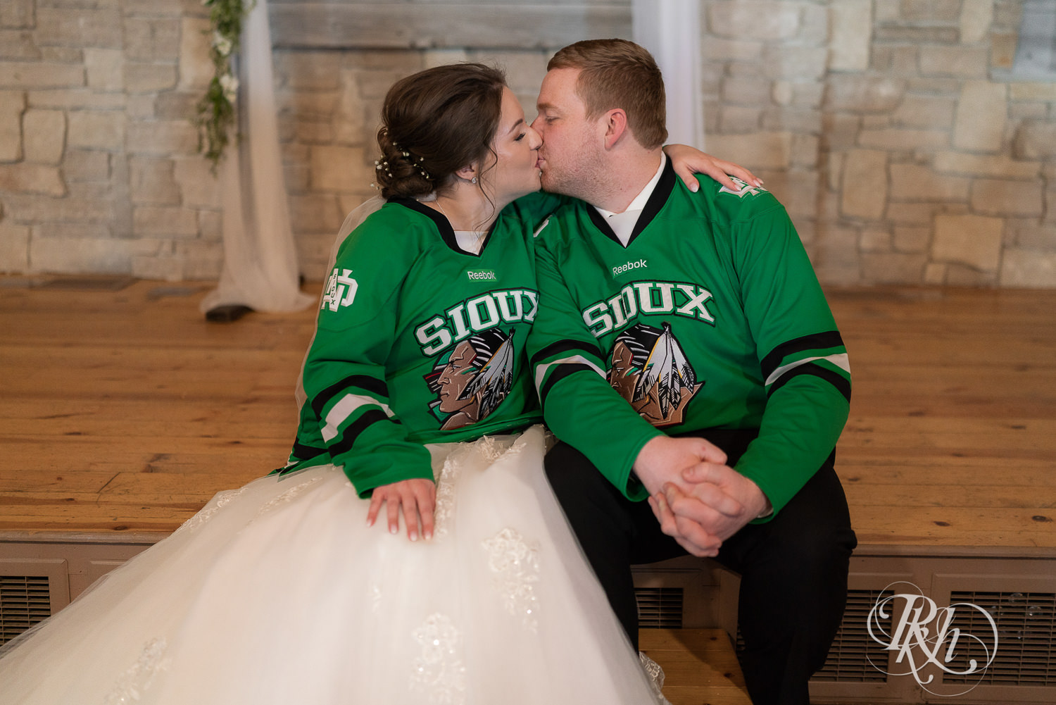 Bride and groom dressed in ND Sioux hockey jerseys at Glenhaven Events in Farmington, Minnesota.