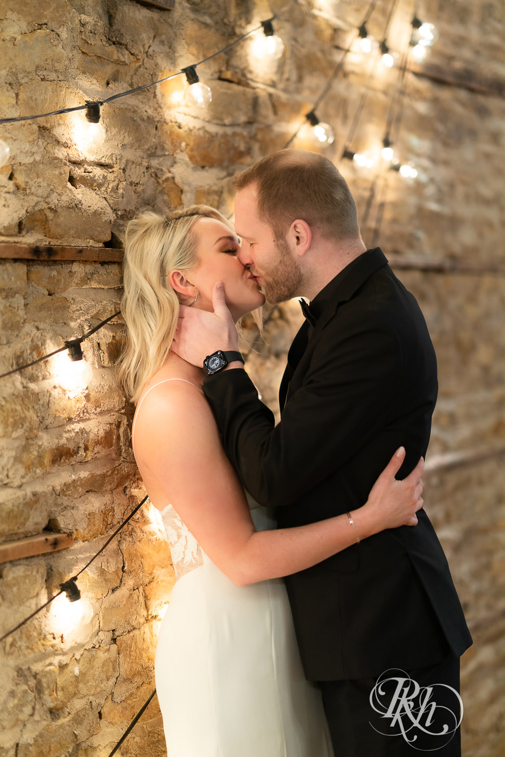 Bride and groom kissing in front of brick wall in 3 Ten Event Venue in Faribault, Minnesota.
