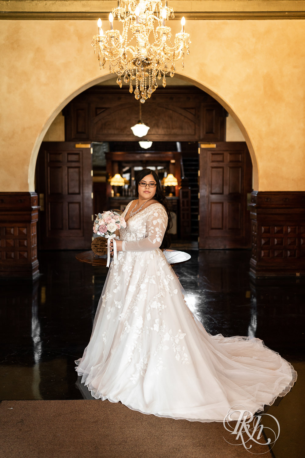 Mexican bride holding flowers under chandelier at the Historic Concord Exchange in Saint Paul, Minnesota.