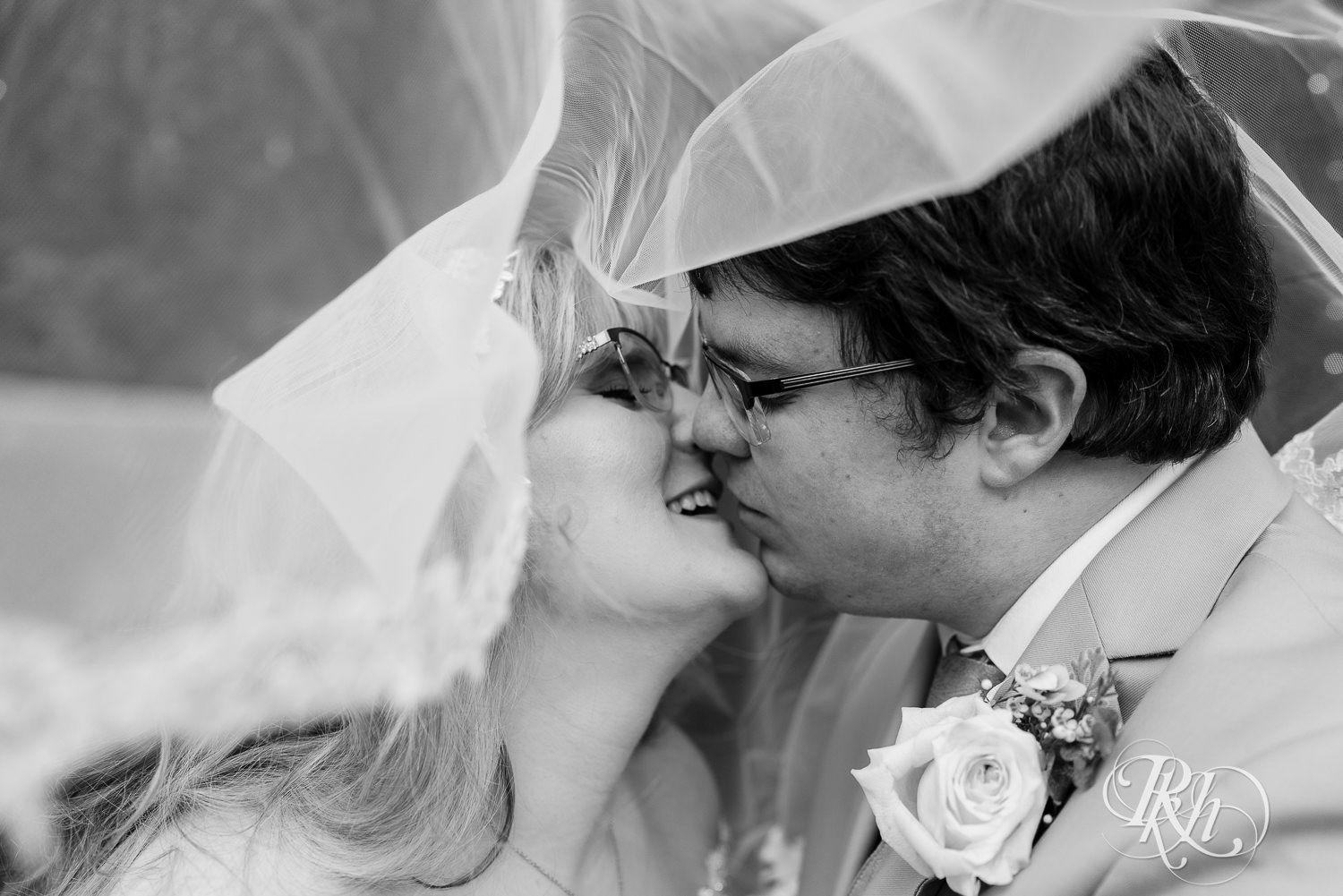 Bride and groom kissing under veil at Hope Glen Farm in Cottage Grove, Minnesota.