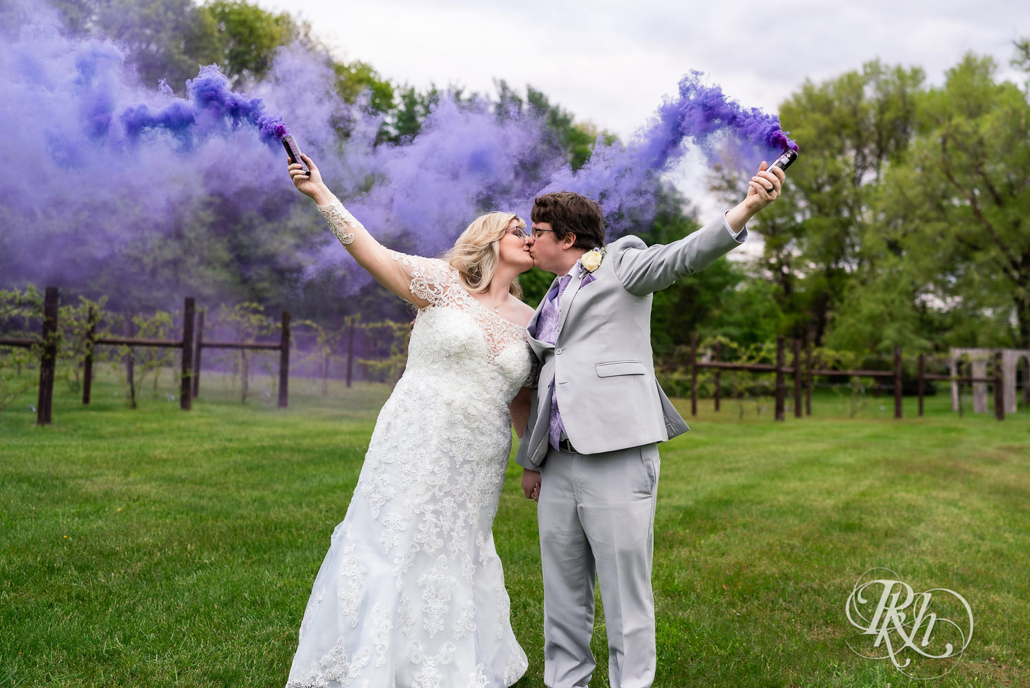 Bride and groom kiss while holding purple smoke bombs at Hope Glen Farm in Cottage Grove, Minnesota.