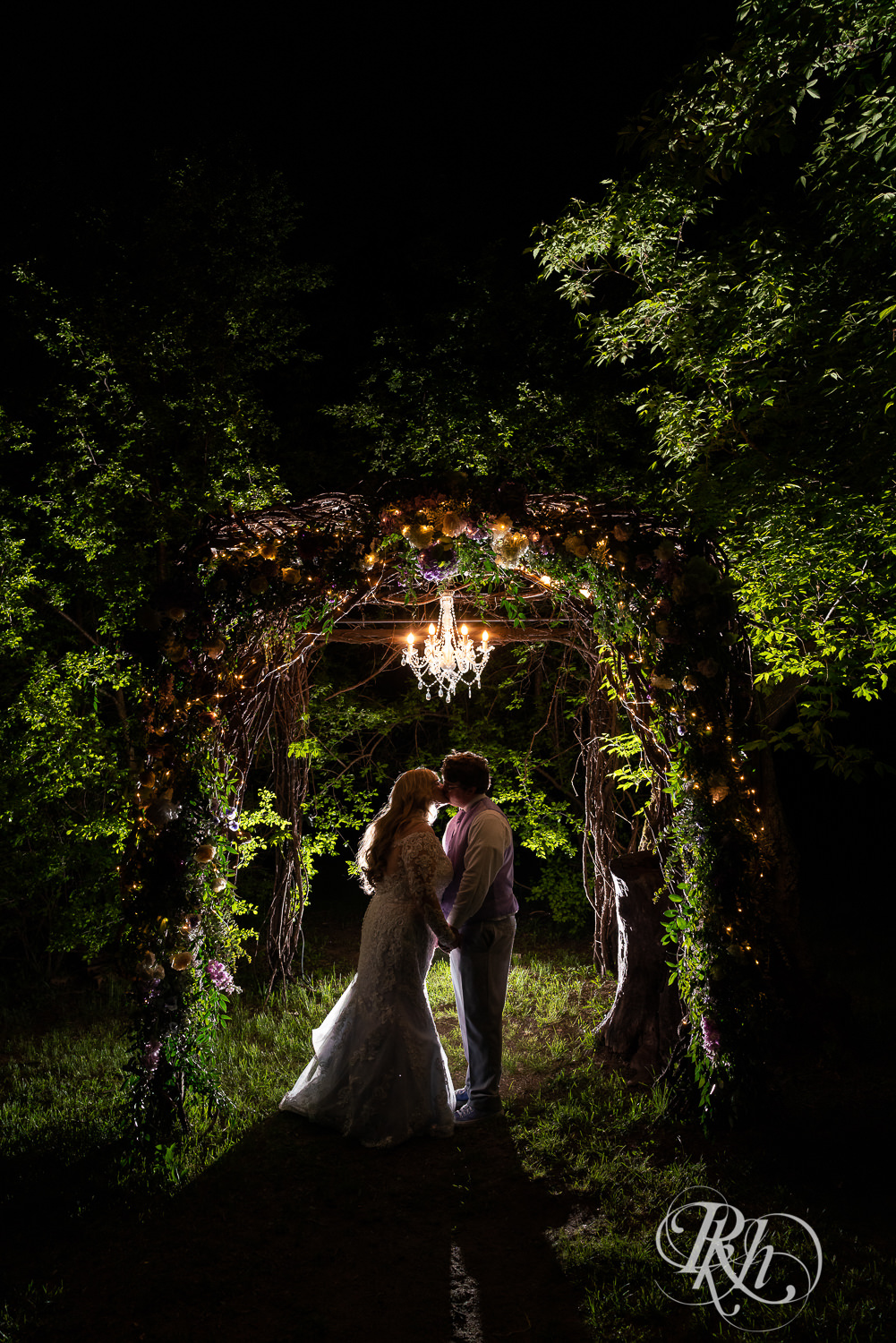 Bride and groom kiss at night under lit alter at Hope Glen Farm in Cottage Grove, Minnesota.