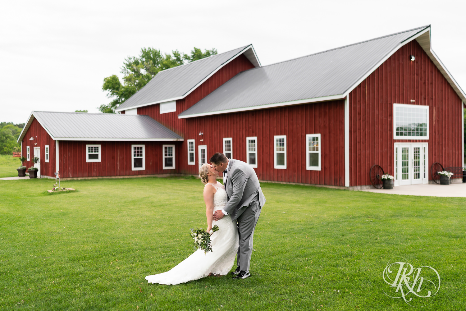 Bride and groom kiss in front of barn at Barn at Mirror Lake in Mondovi, Wisconsin.