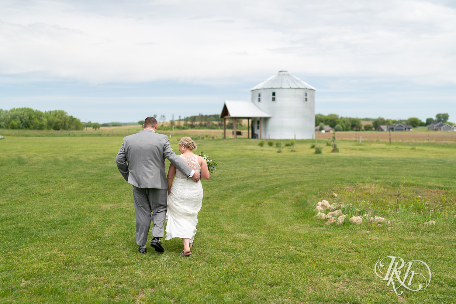 Bride and groom walk across field at Barn at Mirror Lake in Mondovi, Wisconsin.