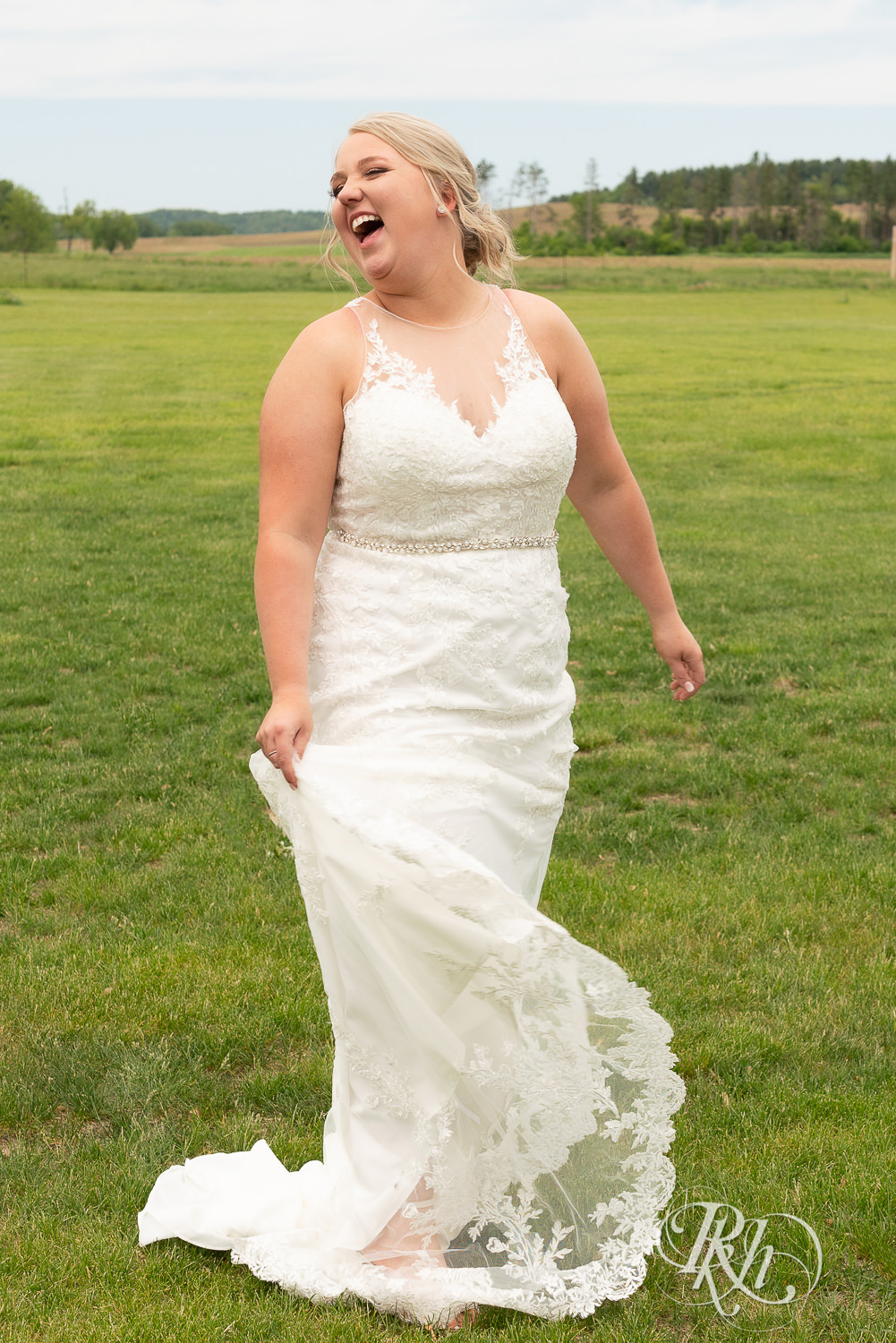 Bride laughs in field at Barn at Mirror Lake in Mondovi, Wisconsin.