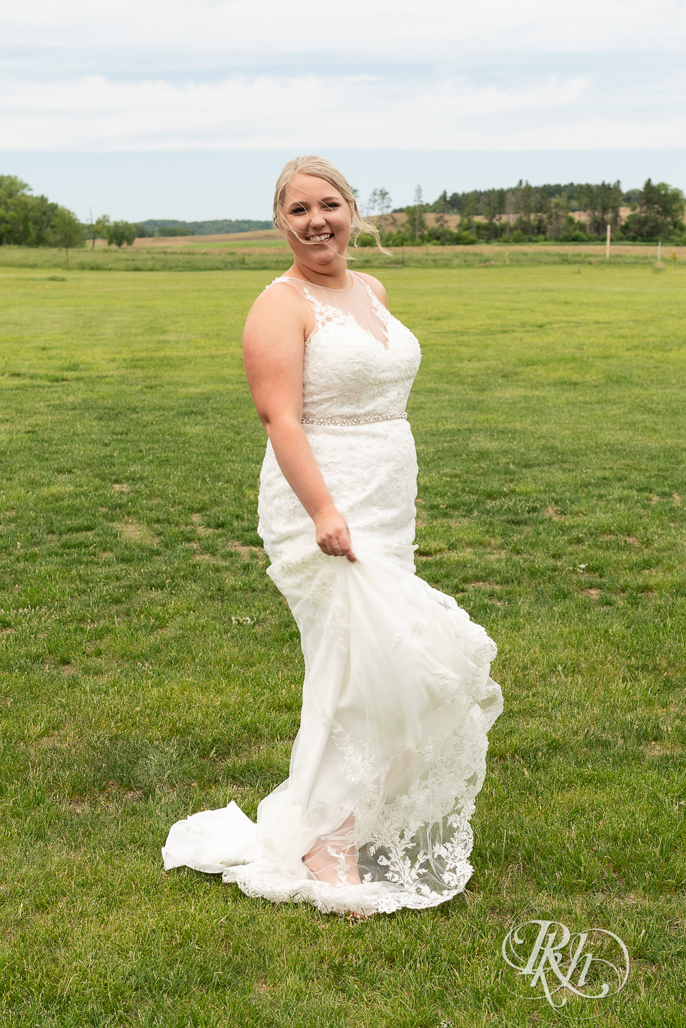Bride laughs in field at Barn at Mirror Lake in Mondovi, Wisconsin.