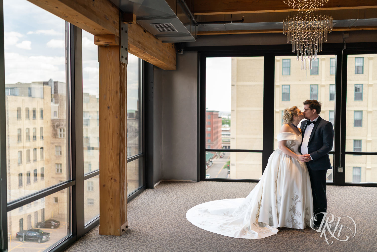 Bride and groom kiss under chandelier at Abulae in Saint Paul, Minnesota.