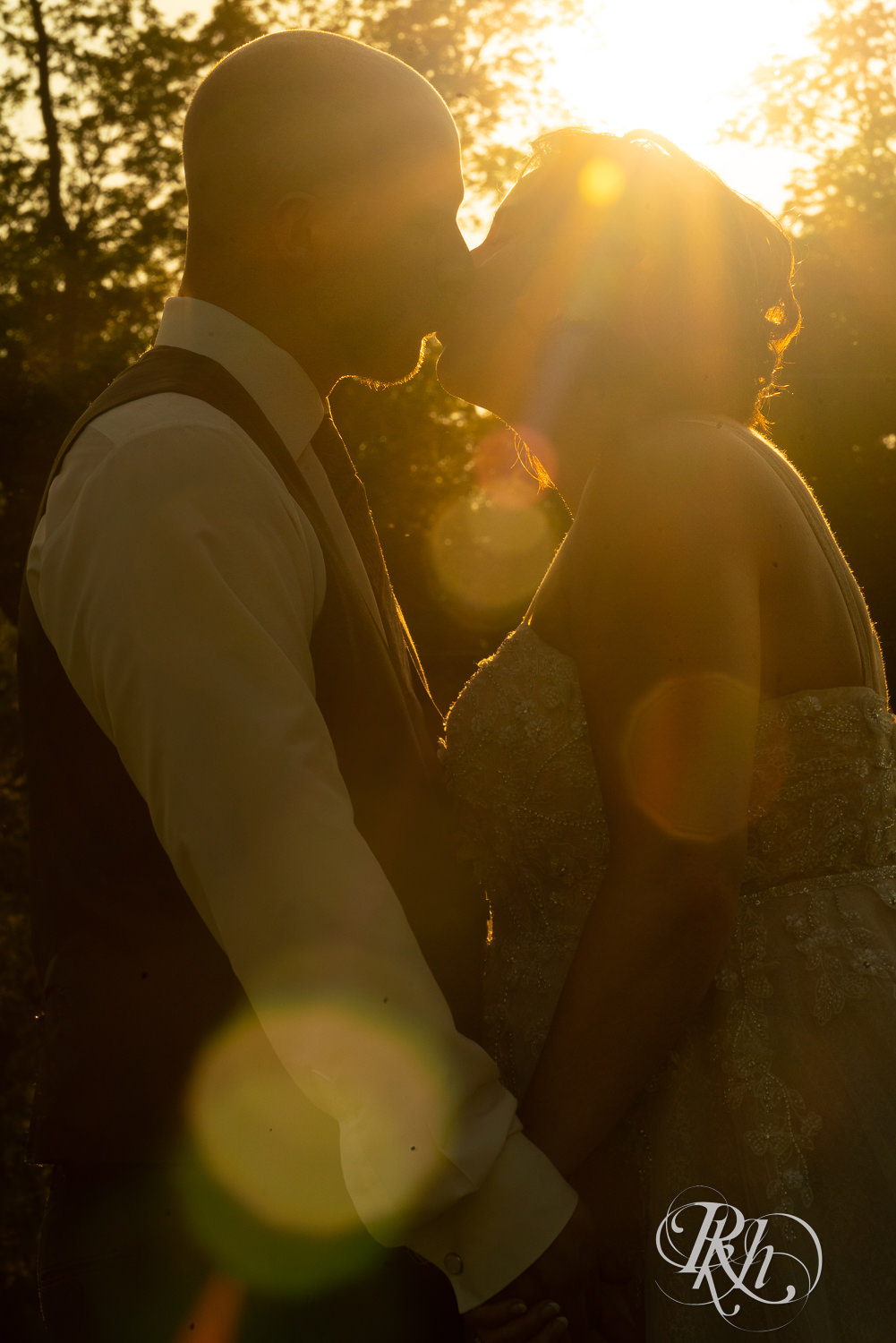 Bride and groom kiss at sunset at Barn at Crocker's Creek wedding in Faribault, Minnesota.