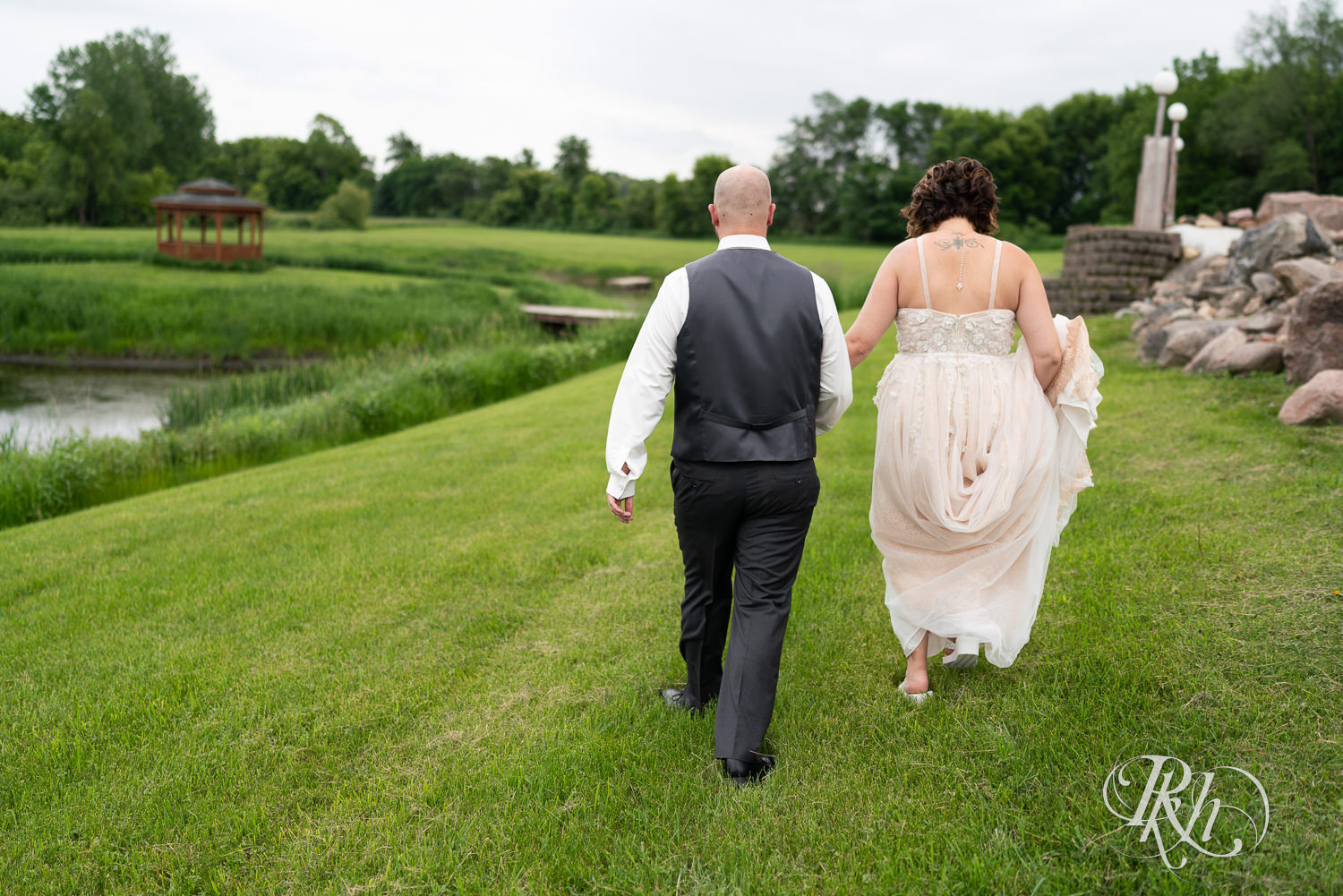 Bride and groom walking in grass at Barn at Crocker's Creek in Faribault, Minnesota.