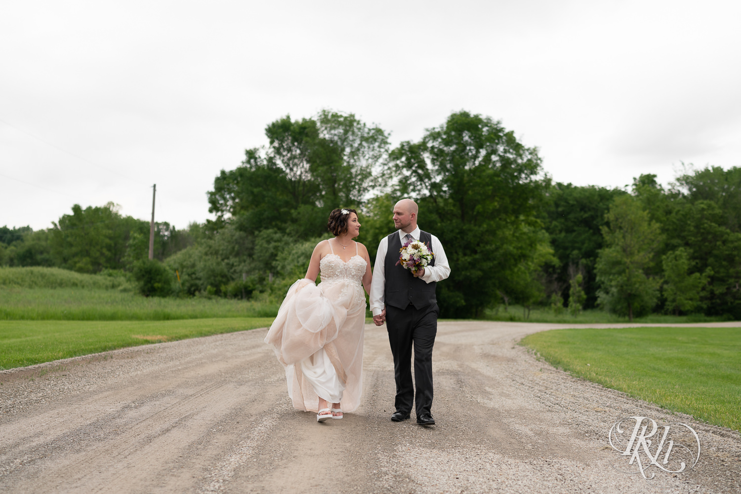 Bride and groom walking down road at Barn at Crocker's Creek in Faribault, Minnesota.