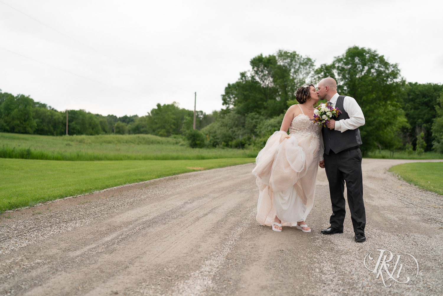 Bride and groom kissing while walking down road at Barn at Crocker's Creek in Faribault, Minnesota.