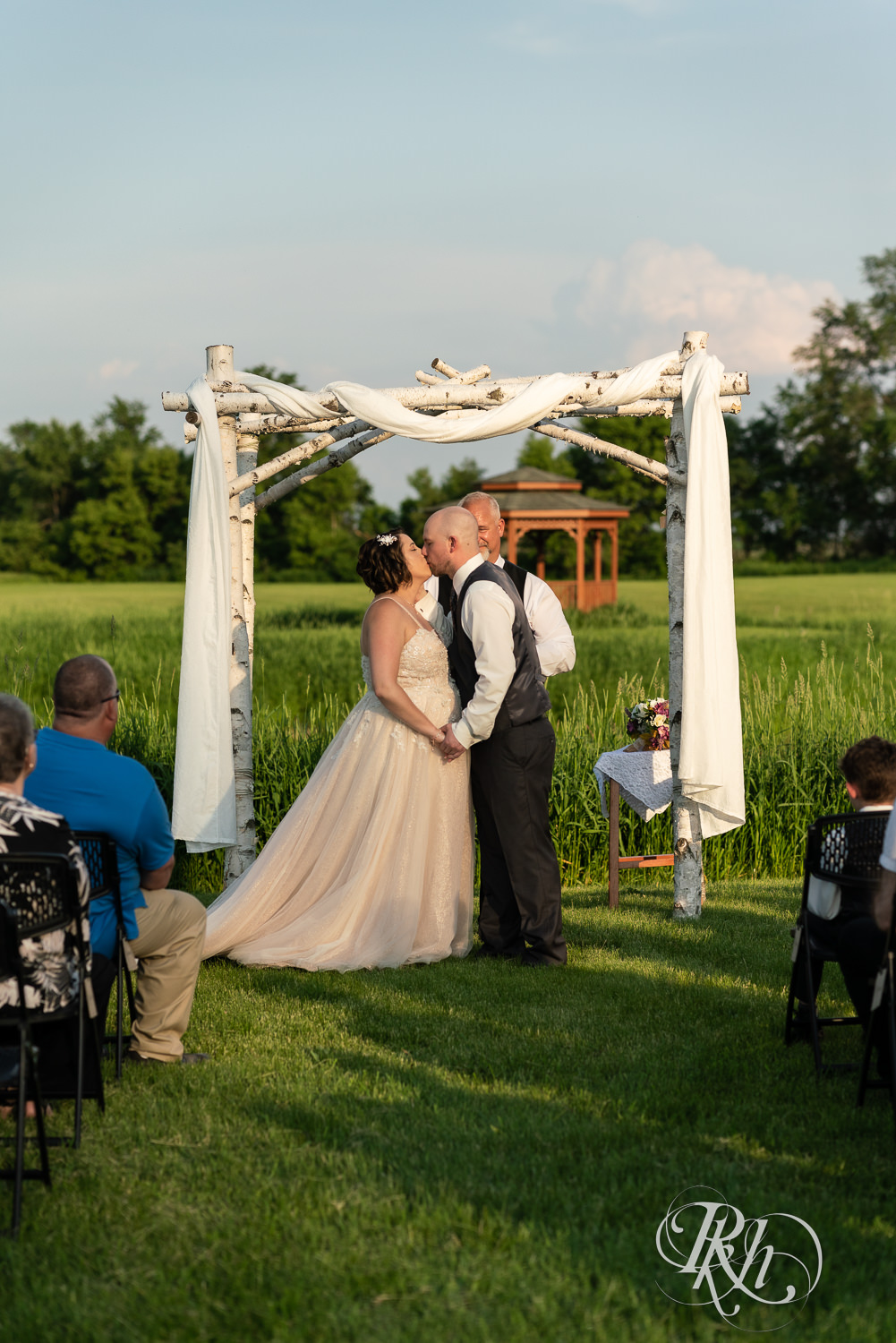 Bride and groom kiss at alter at sunset ceremony at Barn at Crocker's Creek in Faribault, Minnesota.