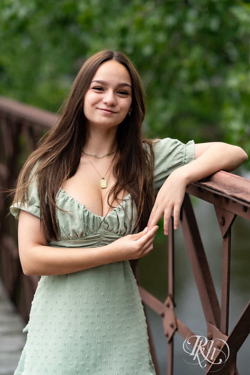 Lexi posing on a bridge in a green dress for senior photography in Minneapolis, Minnesota.