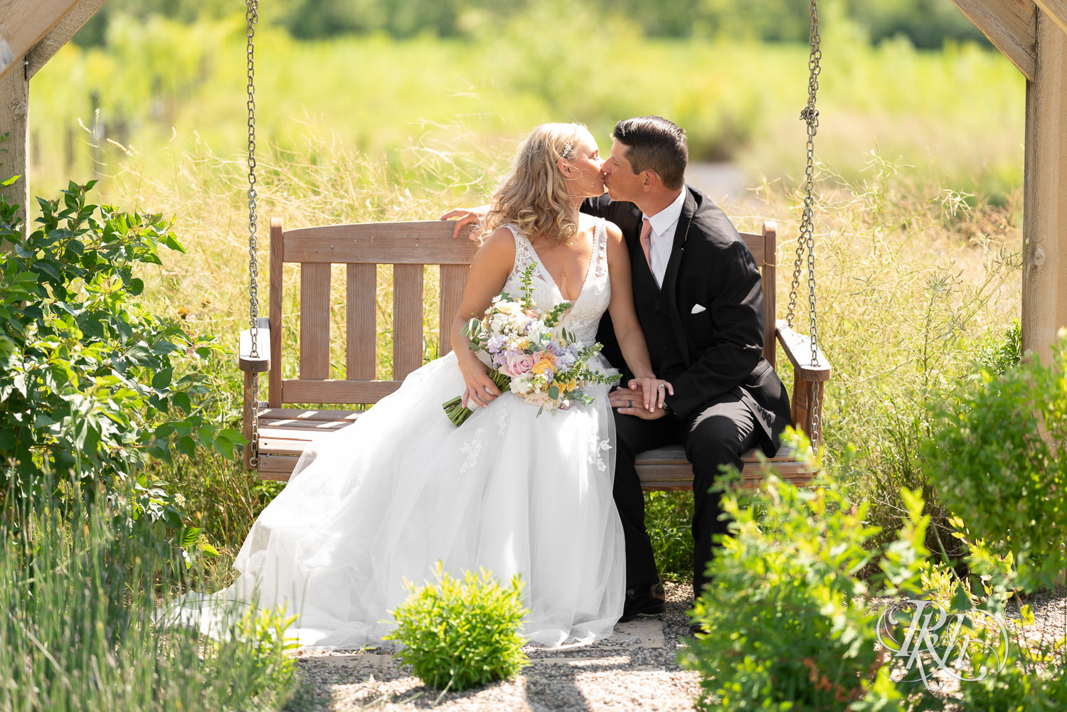 Bride and groom kiss on swing at The Outpost Center in Chaska, Minnesota.