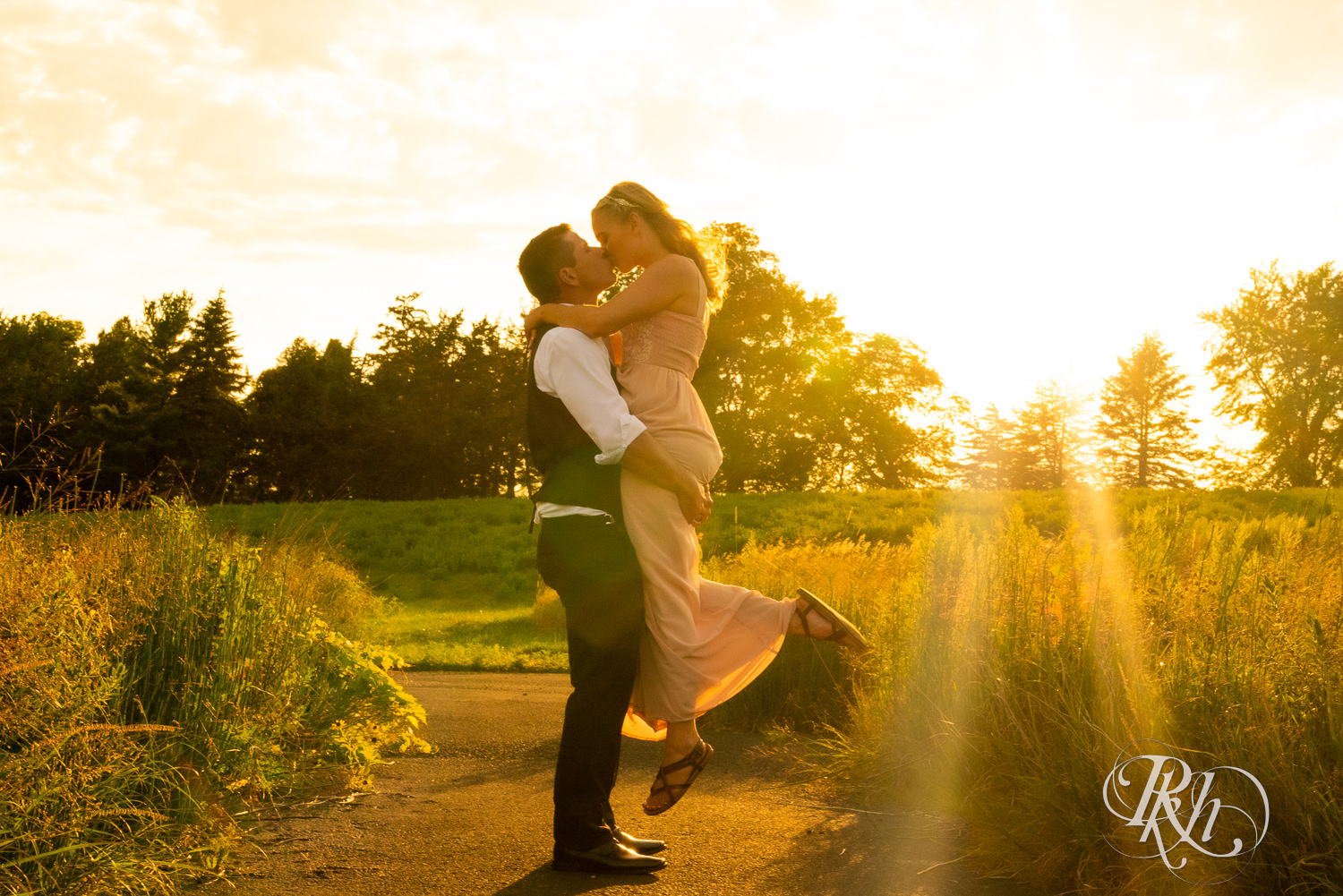 Groom lifting and kissing bride at sunset at The Outpost Center in Chaska, Minnesota.