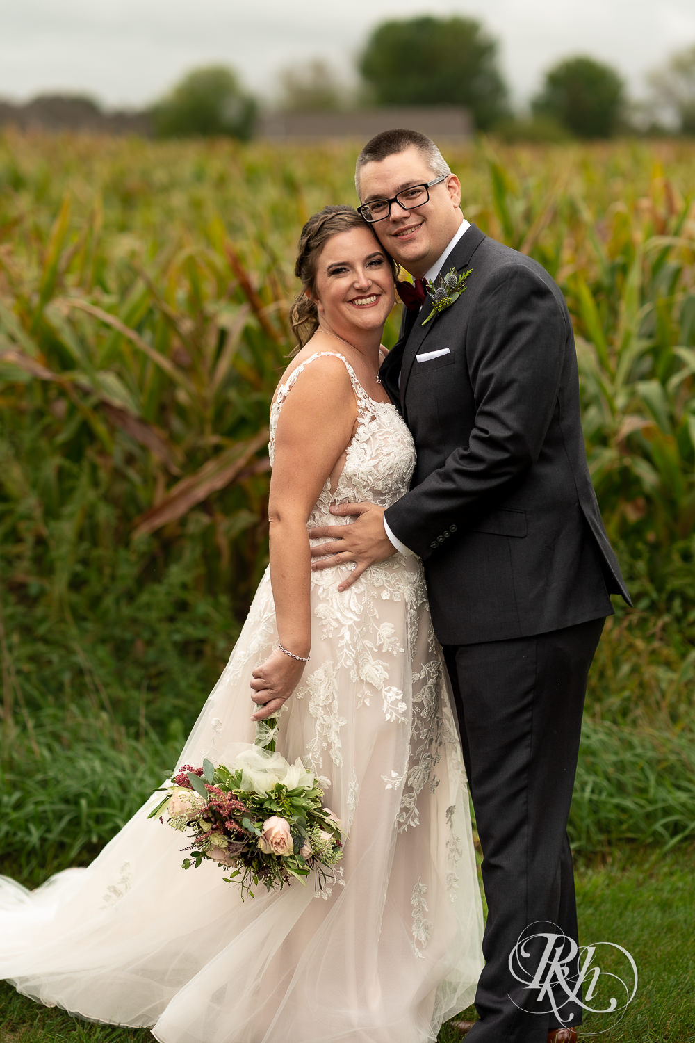 Bride and groom looking at camera in front of cornfield at Glenhaven Events in Farmington, Minnesota.