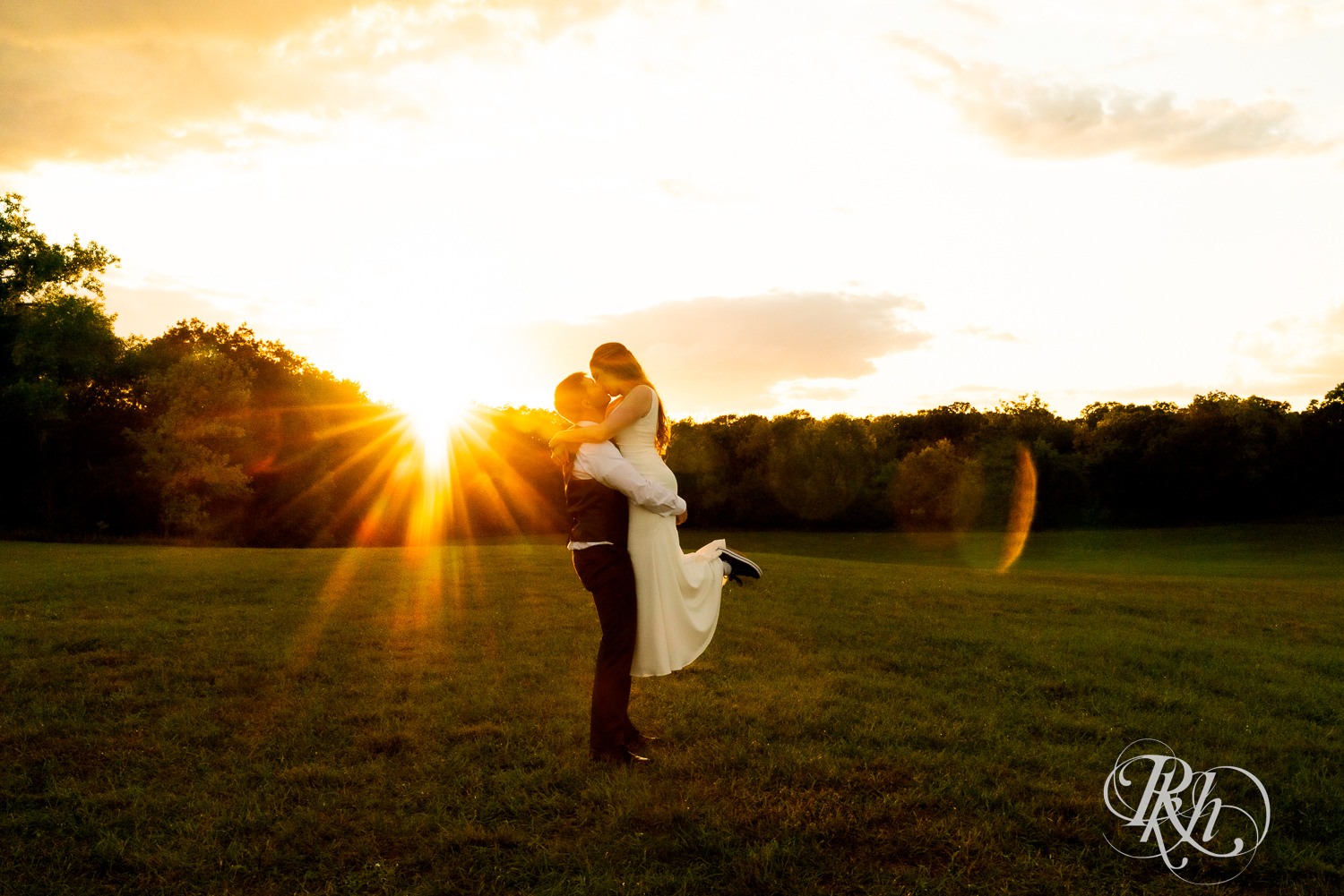 Groom lifting and kissing bride at sunset at Stone Lion Winery and Events in Isanti, Minnesota. 