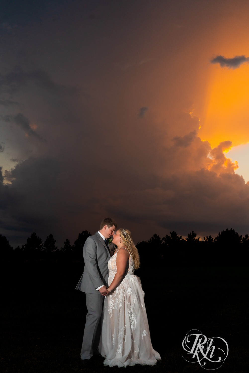 Bride and groom standing in front of an oncoming thunderstorm