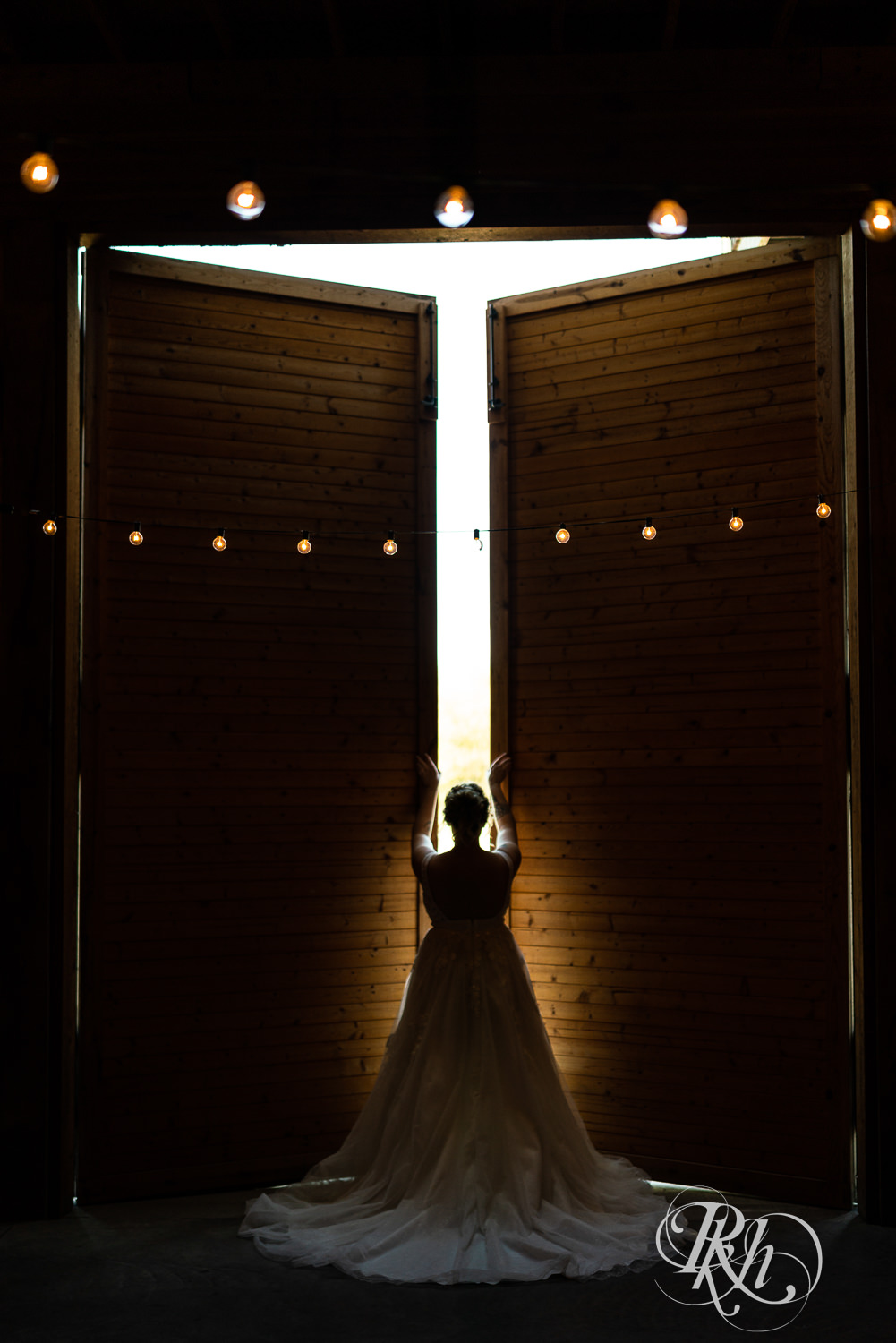 Bride opening barn doors at Barn at Crocker's Creek in Faribault, Minnesota.