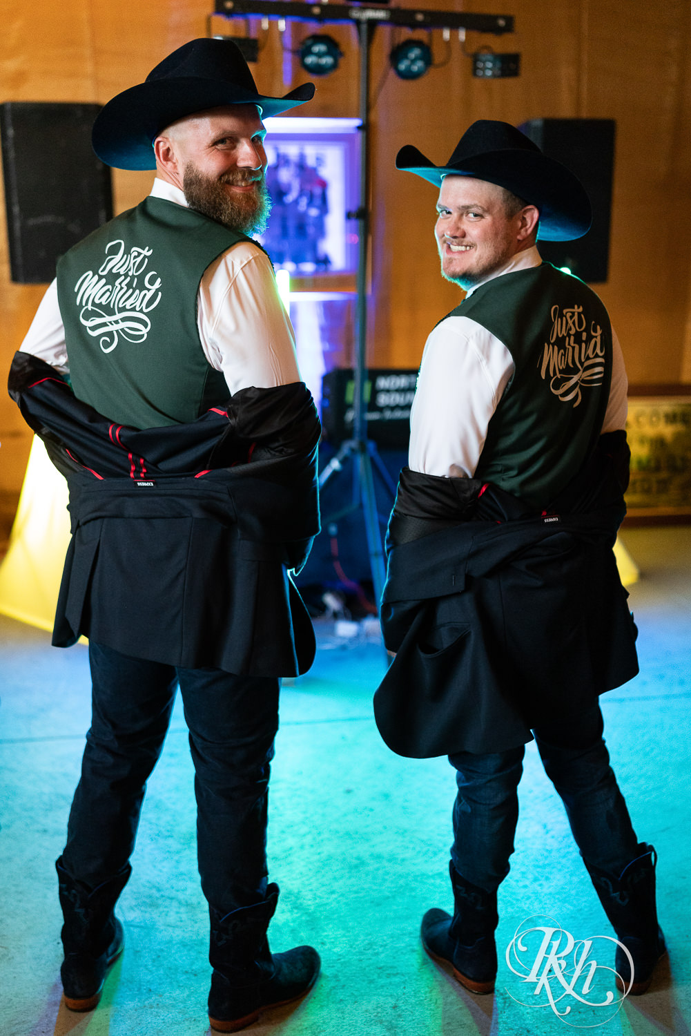 Grooms showing off Just Married vests at their wedding reception. .