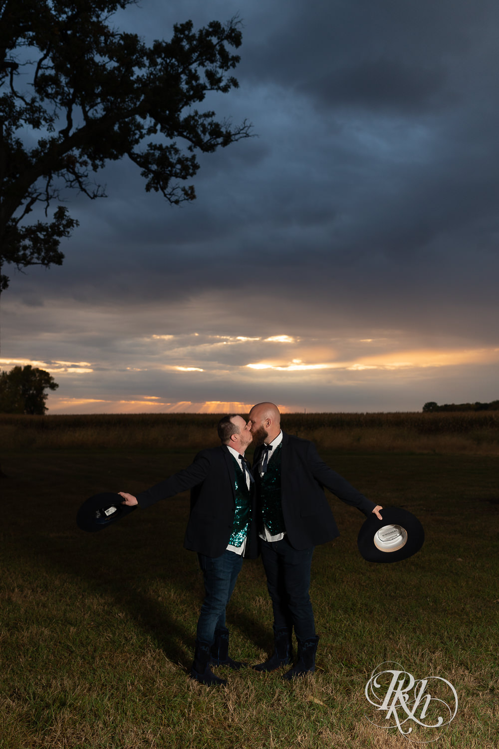 Grooms kissing each other during sunset on their wedding day.