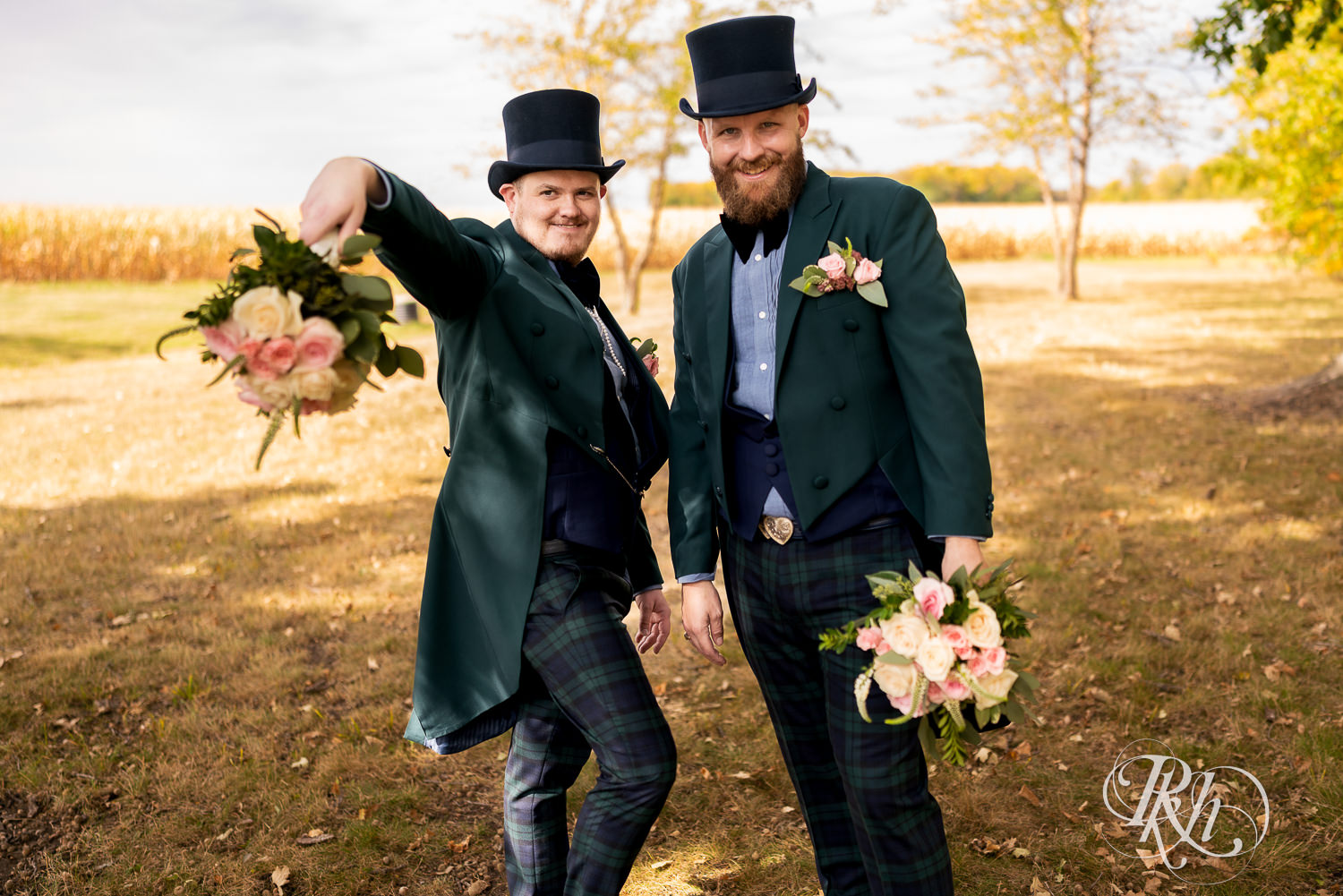 Grooms holding flowers on their wedding day and pointing them at the camera.