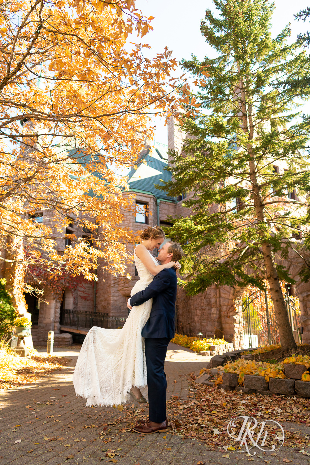 Redhead groom lifting redhead bride in front of the Van Dusen Mansion in Minneapolis, Minnesota in the fall.